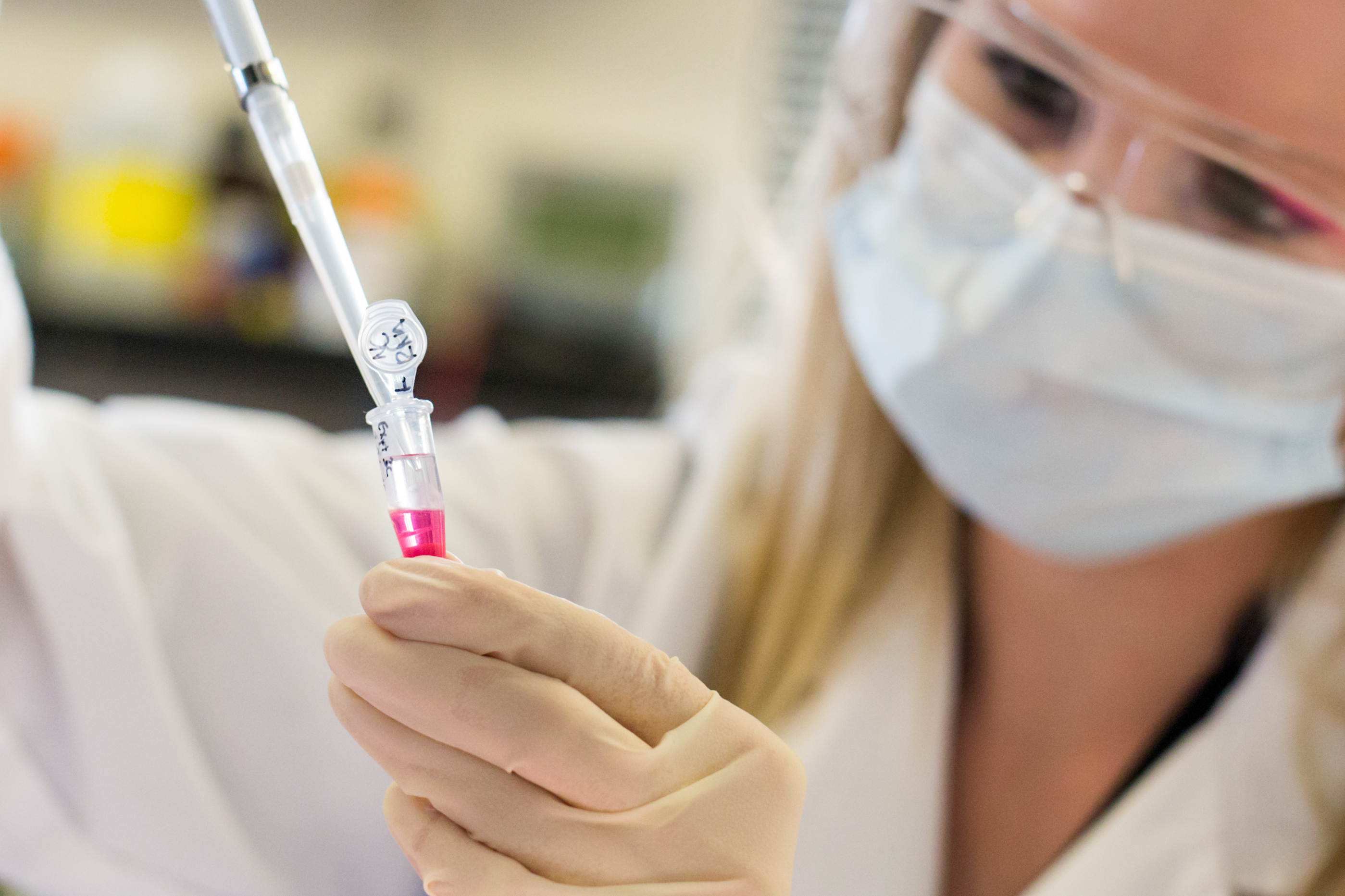 Researcher holding testing vial of pink liquid 