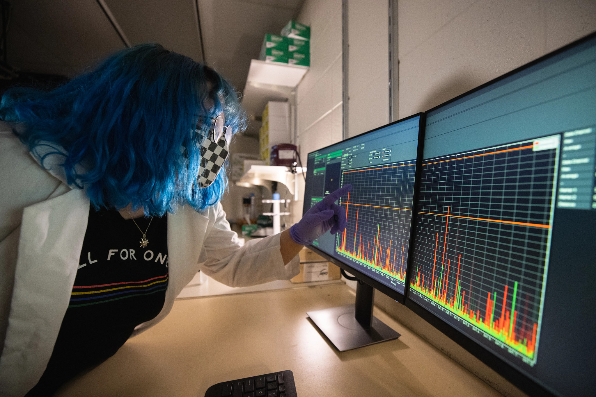 Person studying graphic chart on two computer screens in a lab